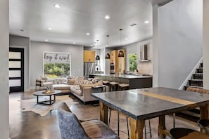 A modern interior with a dining area, kitchen, and seating space. - South Lamar Wellness Haven / Sauna / Hot Tub / BBQ (Austin)