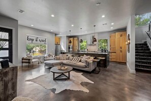 A modern living space with a sofa, coffee table, and a dining area with wooden cabinets.