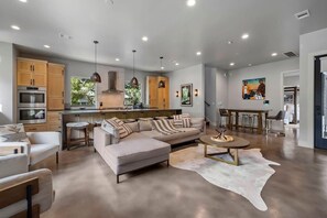 A modern kitchen with built-in appliances, a dining area with a round table, and a living room with a sofa and a coffee table. - South Lamar Wellness Haven / Sauna / Hot Tub / BBQ (Austin)
