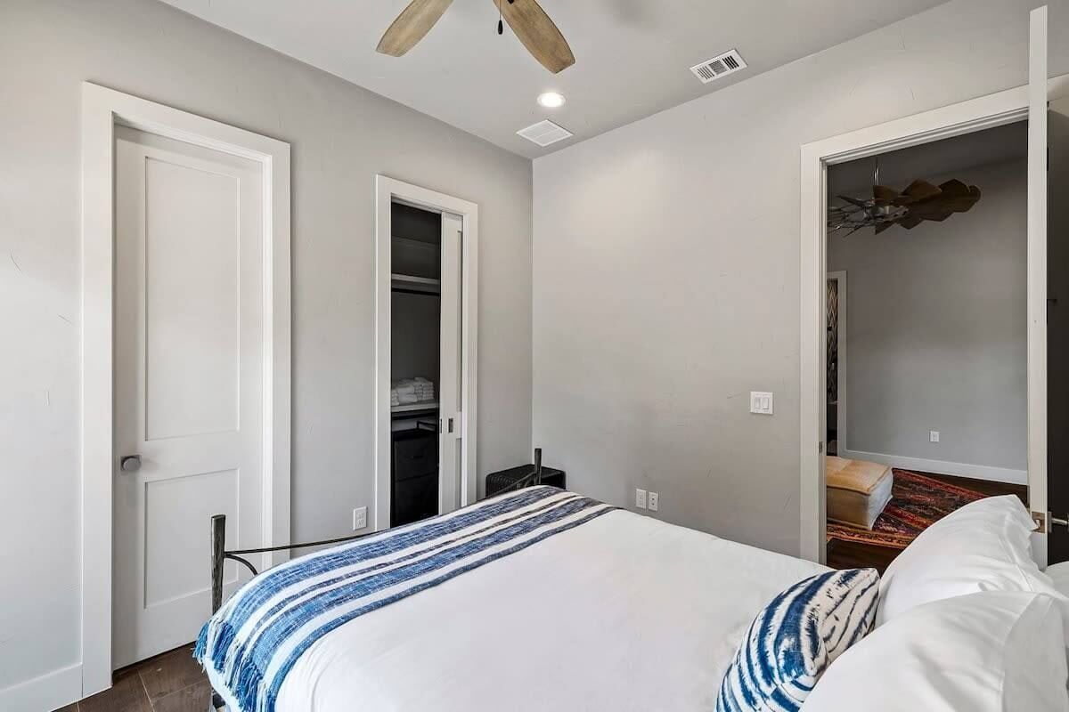 A bedroom with a bed, a closet, and a ceiling fan.
