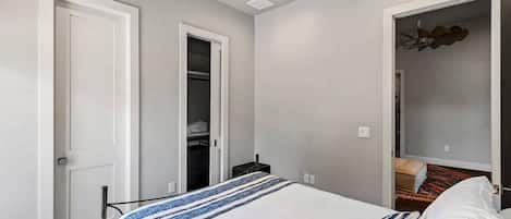 A bedroom with a bed, a closet, and a ceiling fan.