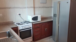 Une cuisine équipée d’une cuisinière à gaz, d’un four, d’un four à micro-ondes, d’un réfrigérateur et d’un évier.