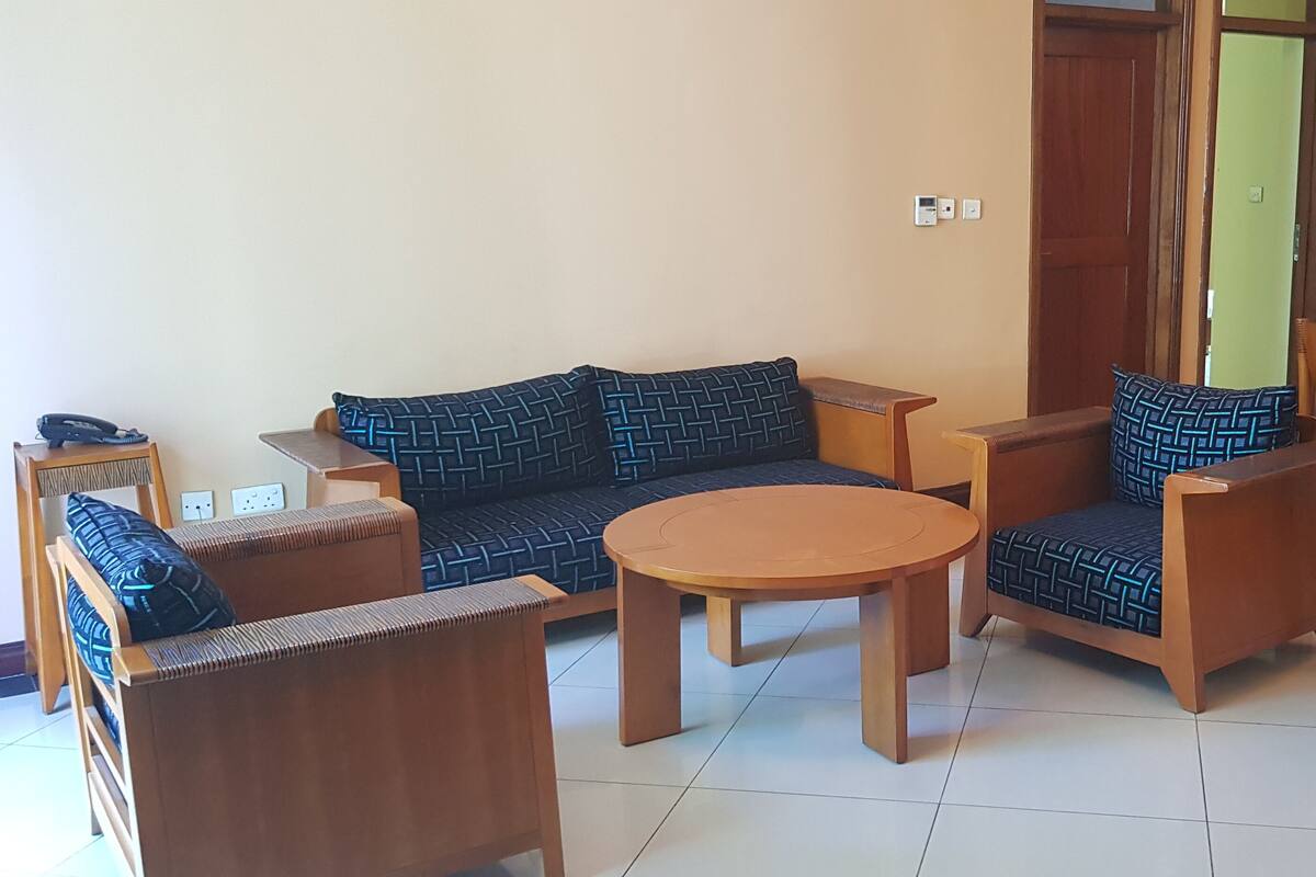 Un salon comprenant un canapé, des fauteuils, une table basse et une table à manger avec des chaises.