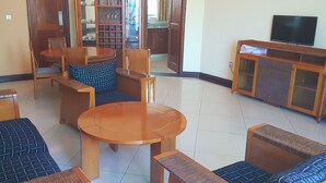 Un salon comprenant un canapé, deux fauteuils, une table basse et un téléviseur.