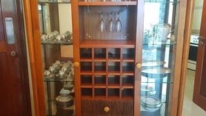Une porte en bois avec une pancarte indiquant de la pousser, un présentoir en verre contenant des ustensiles de cuisine et une étagère avec des verres à vin.