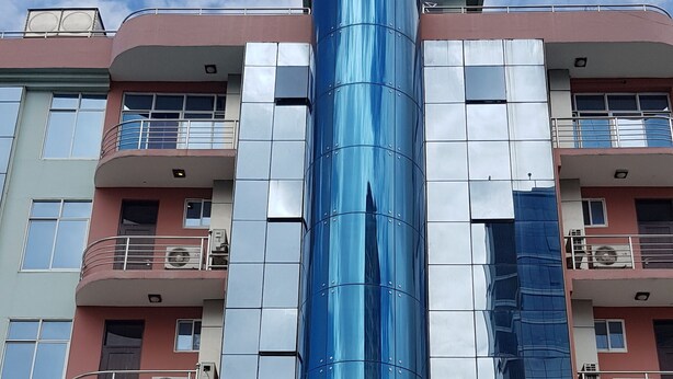 Un hôtel doté d’une façade moderne en verre et d’une enseigne bien visible indiquant « NOUVEL HÔTEL SAFINA ».