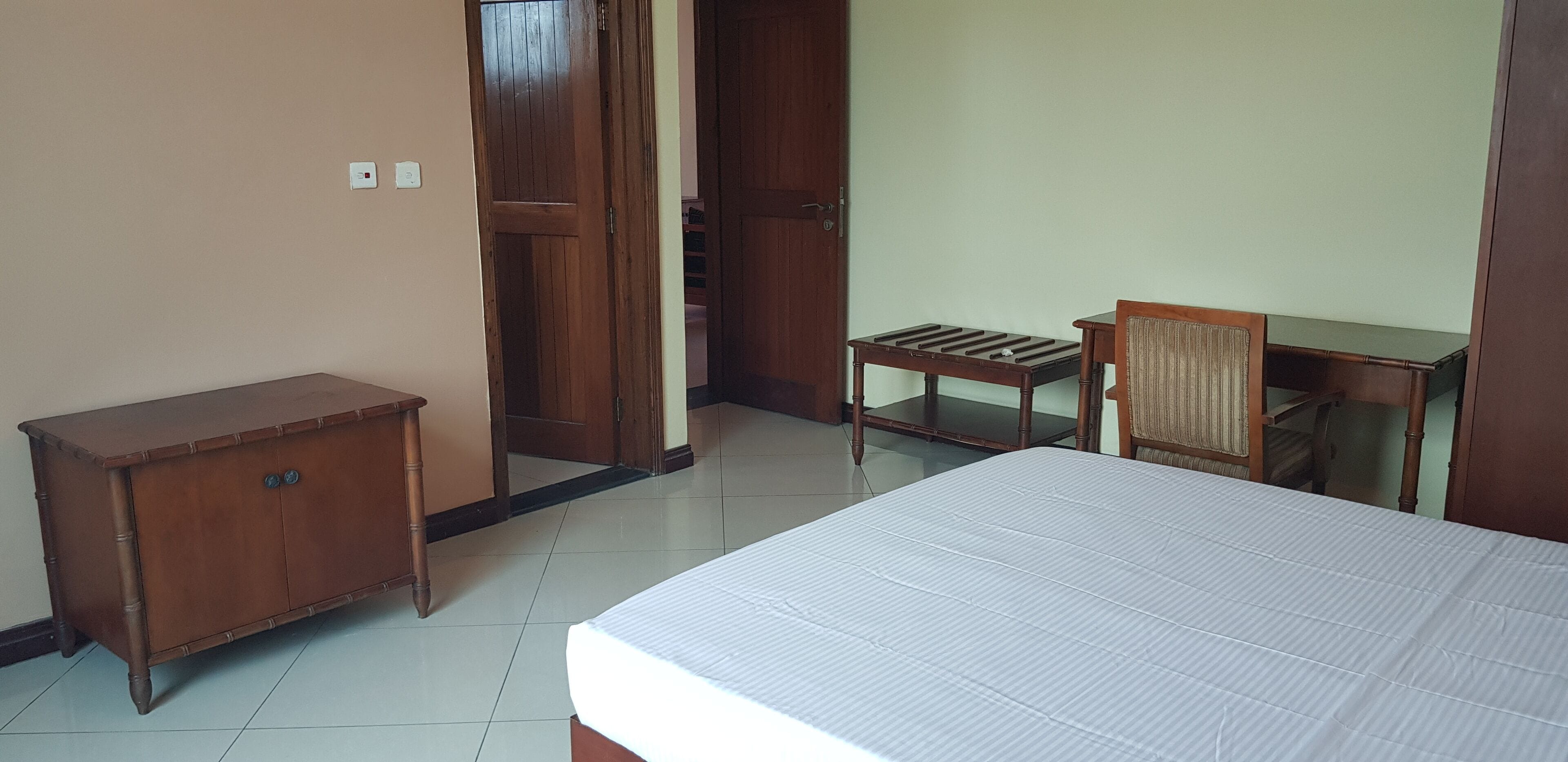 A bedroom with a bed, a wooden cabinet, a chair, and a small table.