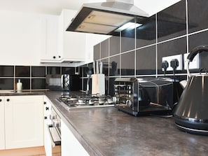 A modern kitchen with white cabinets, a gas stove, a toaster, and a kettle. - 2 bedroom accommodation in Combe Martin (Combe Martin)