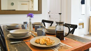 A dining table set with bowls, plates, and a coffee pot. - 2 bedroom accommodation in Combe Martin (Combe Martin)