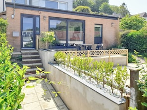 A modern house with a patio area, a small garden, and a seating area with a table and chairs. - 2 bedroom accommodation in Combe Martin (Combe Martin)