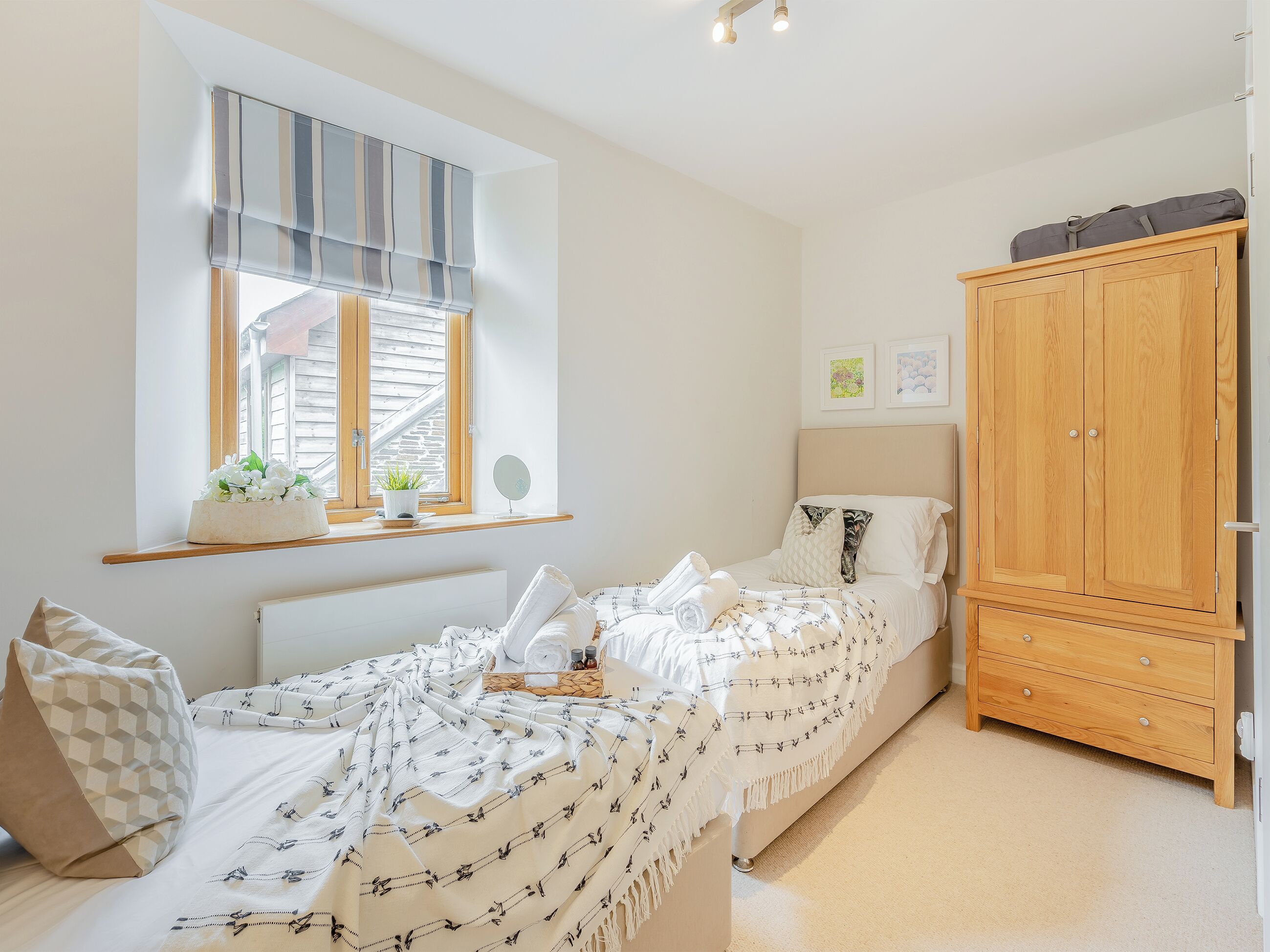 A bedroom with a bed, bedside table, window with curtains, and a wardrobe.
