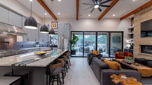 Una cocina moderna con una isla grande, taburetes de bar y una zona de comedor con sofá y mesa de centro.