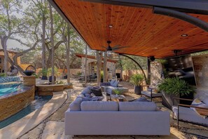 An outdoor seating area with a wooden pergola, a pool, and stone walls. - Luxury Retreat | Near Austin at Always on My Mind (Austin)