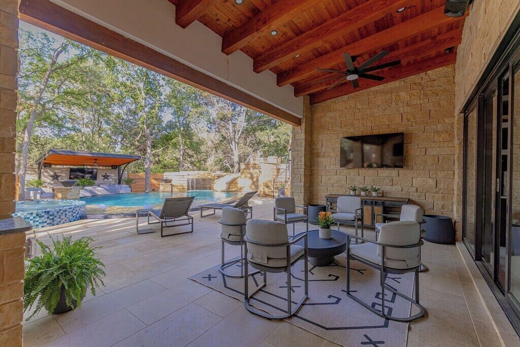 Une terrasse extérieure avec un mur en pierre, une piscine et un espace détente avec des chaises et une table.