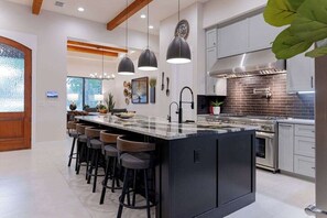 A modern kitchen with a central island, bar stools, pendant lighting, and stainless steel appliances. - Luxury Retreat | Near Austin at Always on My Mind (Austin)