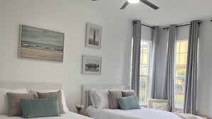 Quarto com duas camas, um ventilador de teto e uma janela com cortinas.