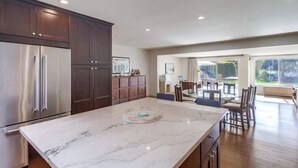A modern kitchen with dark wooden cabinets, stainless steel appliances, and a marble countertop. - Ocean & Bay View Retreat | A/C & Private Yard (San Diego)
