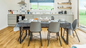 Une cuisine moderne dotée d’un îlot central, de luminaires suspendus et offrant une vue sur l’extérieur.