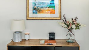 Un tableau encadré, une lampe, un vase avec des fleurs, un carnet et une bougie sur une table en bois.