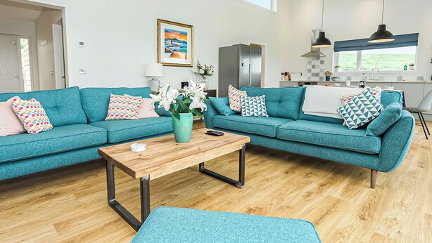 Un salon moderne avec un canapé turquoise, une table basse en bois et un tapis bleu.