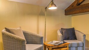 Una habitación acogedora con dos sillones a cuadros, una mesita de madera y una lámpara de pie.