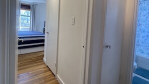 Een gang met houten vloeren, witte muren en deuren die leiden naar slaapkamers.