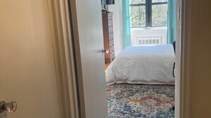 Een slaapkamer met een bed, een dressoir en een raam met gordijnen.