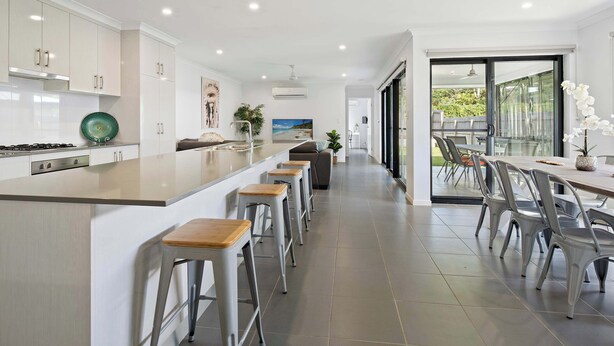 Une cuisine moderne dotée d’un grand îlot central, de tabourets de bar et d’un coin repas avec des chaises et une table.