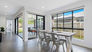 Une pièce spacieuse dotée d’une grande porte-fenêtre coulissante donnant sur une terrasse, d’une table à manger avec des chaises et d’une plante en pot.