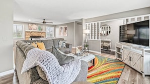 Ein modernes Wohnzimmer mit grauem Sofa, einem Couchtisch und einem Fernseher.