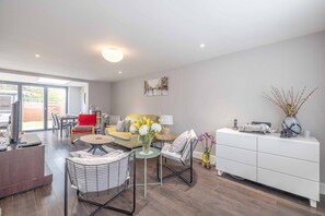 Un salon moderne avec un canapé, des fauteuils, une table basse et un meuble blanc.