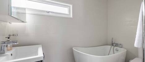 Une salle de bain moderne avec une baignoire sur pieds, un lavabo et des toilettes.
