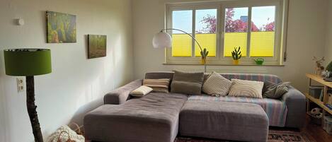 Uma sala de estar aconchegante com um sofá seccional, um tapete estampado e uma luminária.