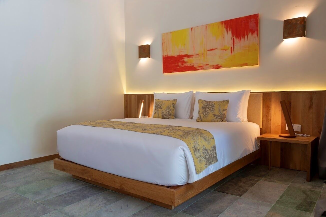Ein modernes Schlafzimmer mit einem großen Bett, einem hölzernen Kopfteil und einem farbenfrohen, abstrakten Gemälde darüber.