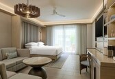 A modern hotel room with a bed, sofa, TV, and a dining area.
