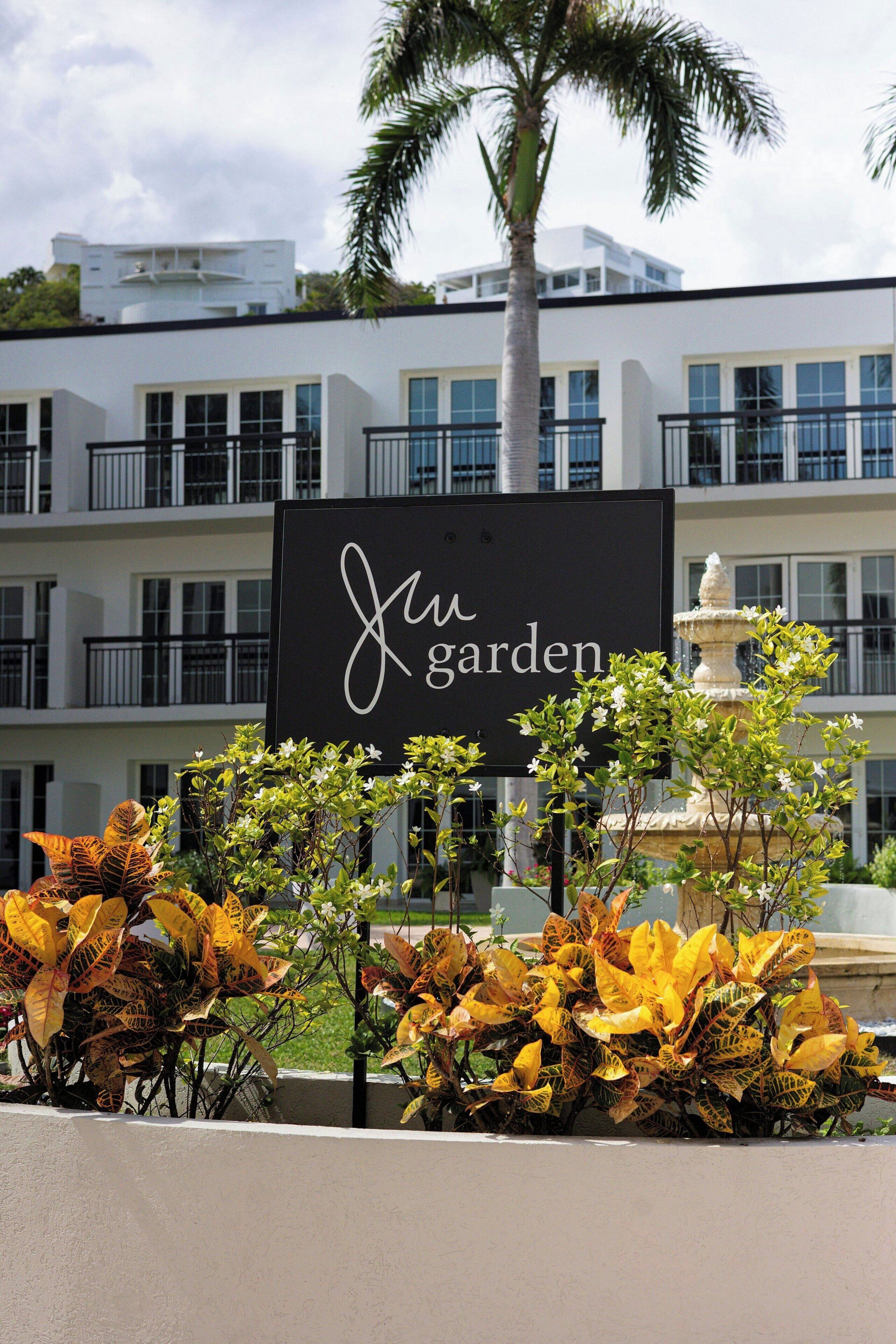 A sign reading 'Juw Garden' with a fountain and ornamental plants in the foreground.