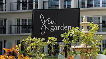 A sign reading 'Juw Garden' with a fountain and ornamental plants in the foreground.