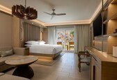 A modern hotel room with a bed, a desk, a sofa, and a dining table.