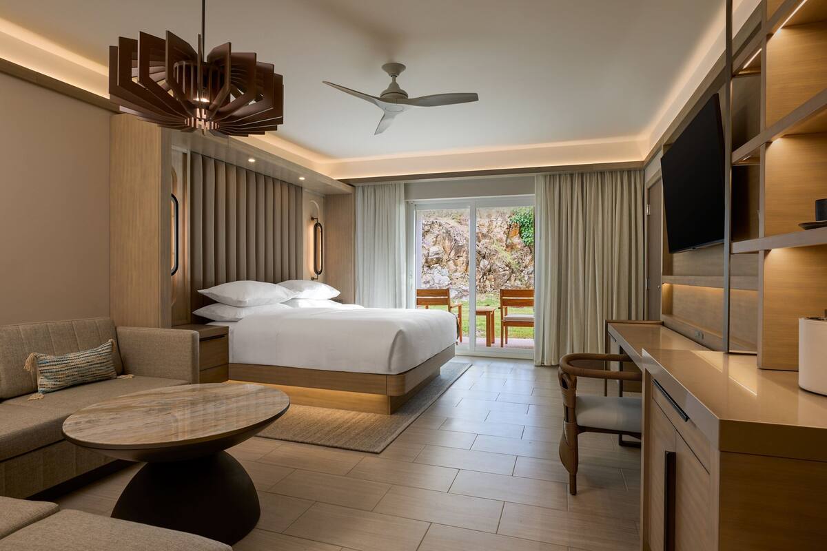 Una habitación de hotel moderna con cama, escritorio, sofá y mesa de comedor.