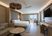 A modern hotel room with a large bed, a sofa, a desk, and a TV.