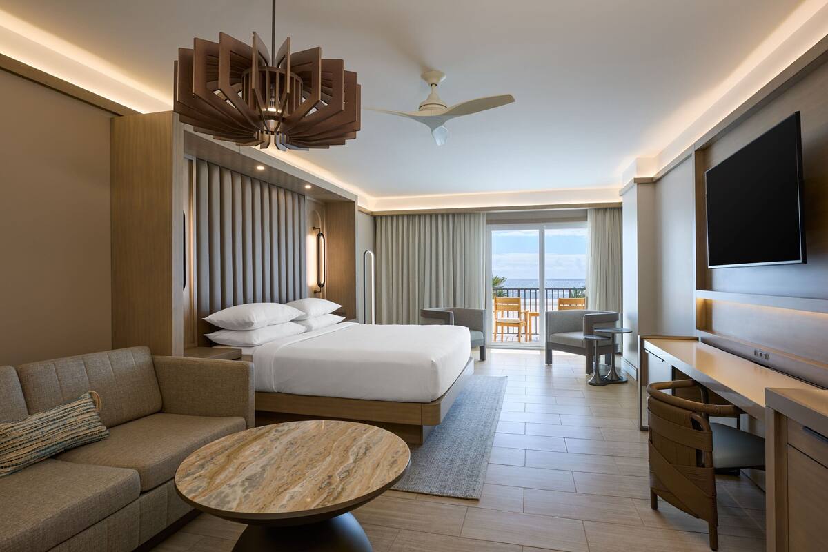 Una habitación de hotel moderna con una cama grande, un sofá, un escritorio y un televisor.
