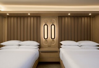 A hotel room with two beds, a wooden headboard, and a built-in light fixture.