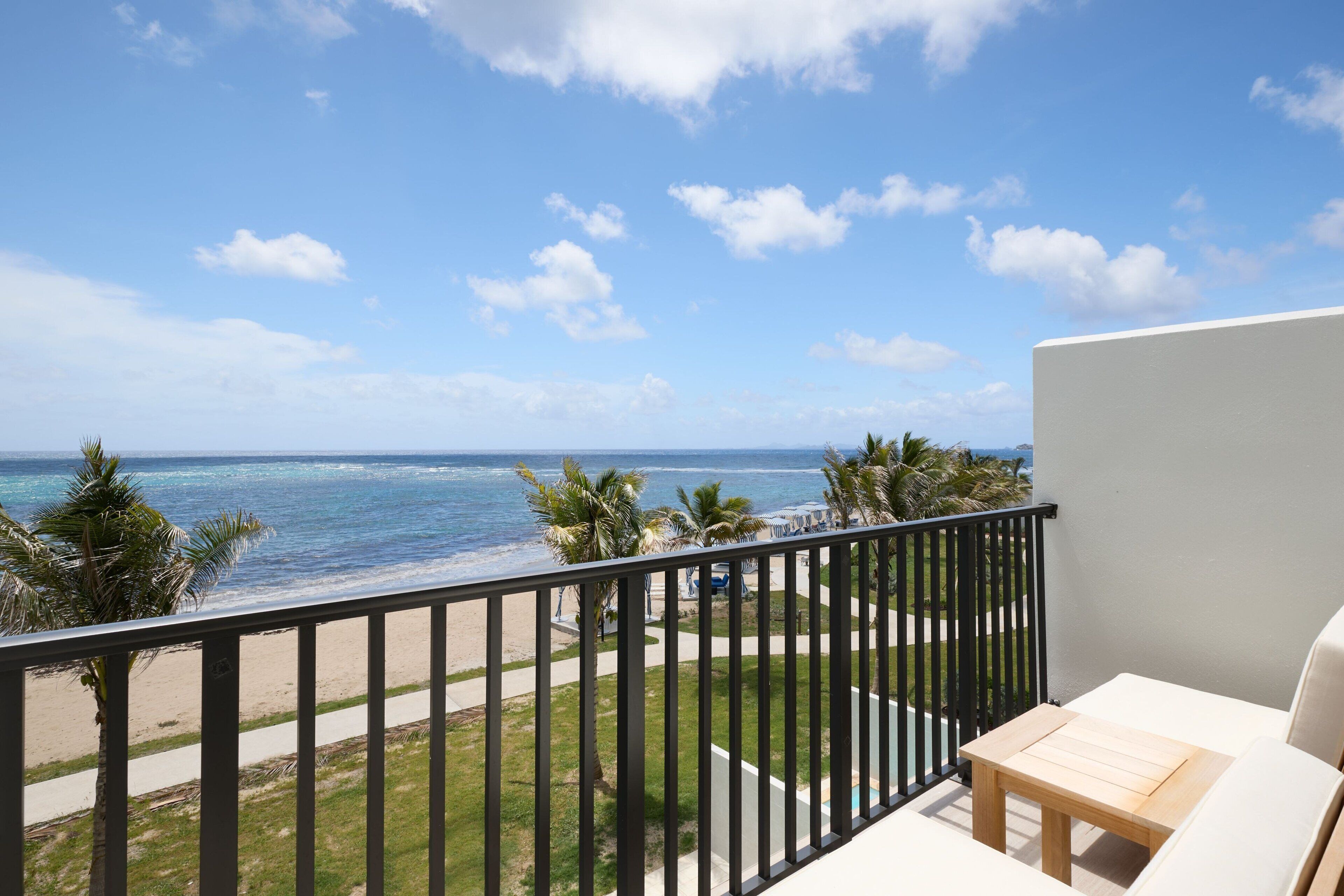 A balcony with a view of the beach and ocean.