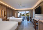 A hotel room with two beds, a desk, a TV, and a balcony with a view.