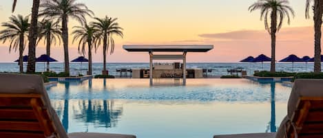 Una piscina al aire libre, camas de piscina con cargo, sombrillas