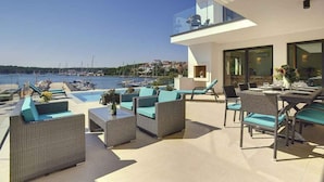 A modern outdoor patio with wicker furniture and a dining area overlooking a marina.