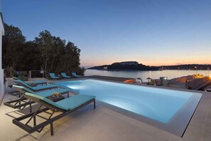A swimming pool with lounge chairs, a view of the sea, and a distant island. - Villa mit Pool und Meerblick (Pješćana Uvala)