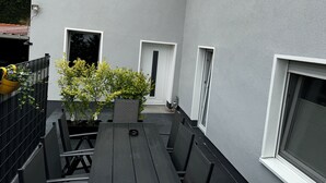 A narrow outdoor corridor with a wooden bench, potted plants, and a small statue. - Maja Ferienwohnung (Brück)