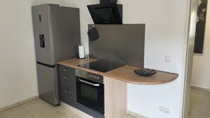 A compact kitchen with a built-in oven, a stainless steel refrigerator, and a wooden countertop. - Maja Ferienwohnung (Brück)