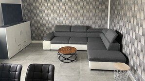 A modern living room with a sectional sofa, a coffee table, and two chairs. - Maja Ferienwohnung (Brück)